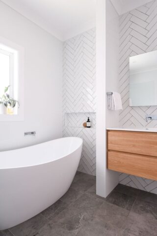 renovated bathroom with white herringbone wall tiles and timber vanity